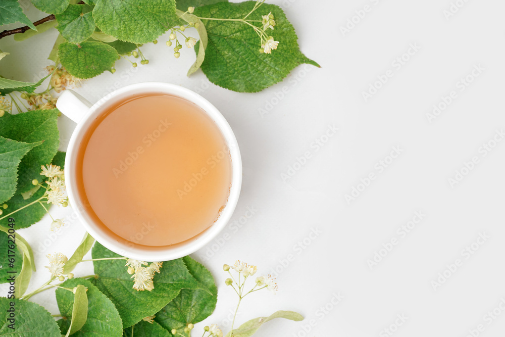 Cup of linden tea and leaves on white background