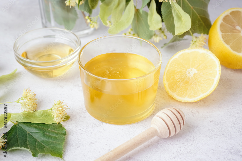 Glass bowl and plate with linden honey on light background