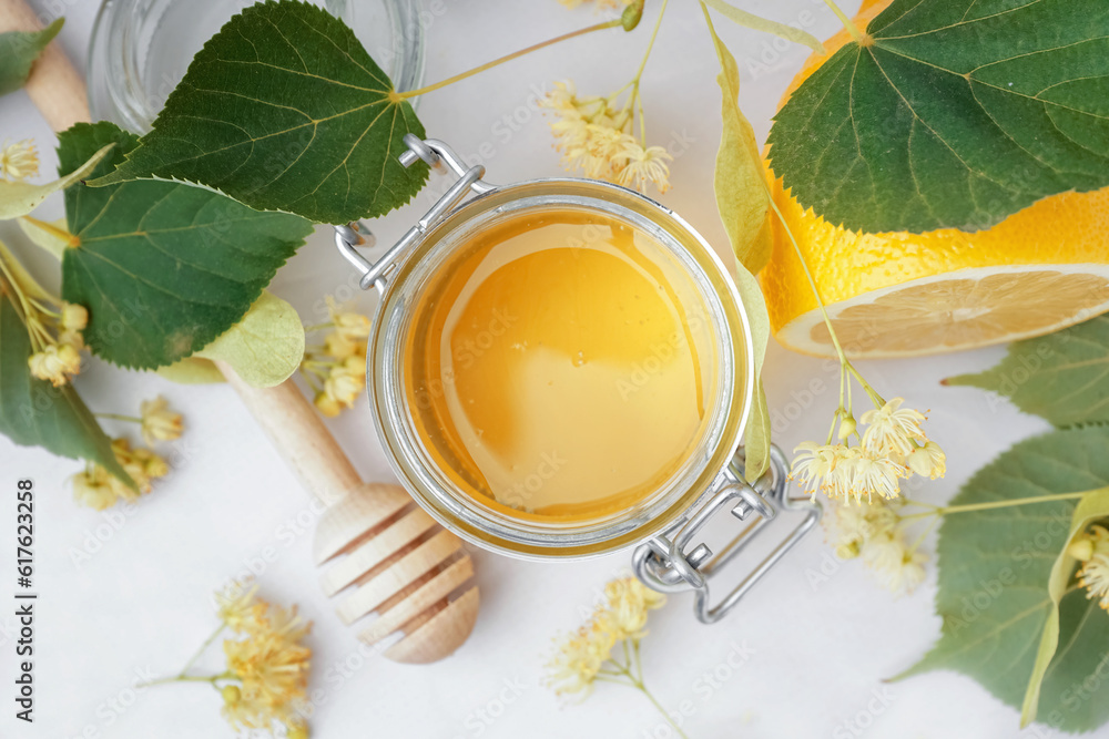 Jar with linden honey and lemon on white background