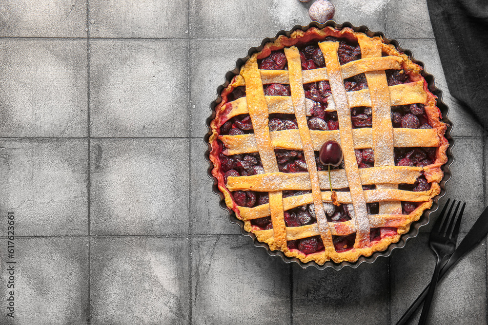 Baking dish with tasty cherry pie on grey tile background