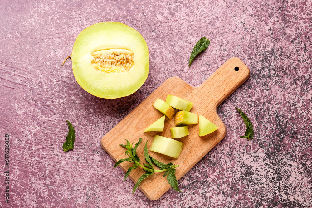 Half of sweet melon and wooden board with pieces on purple background