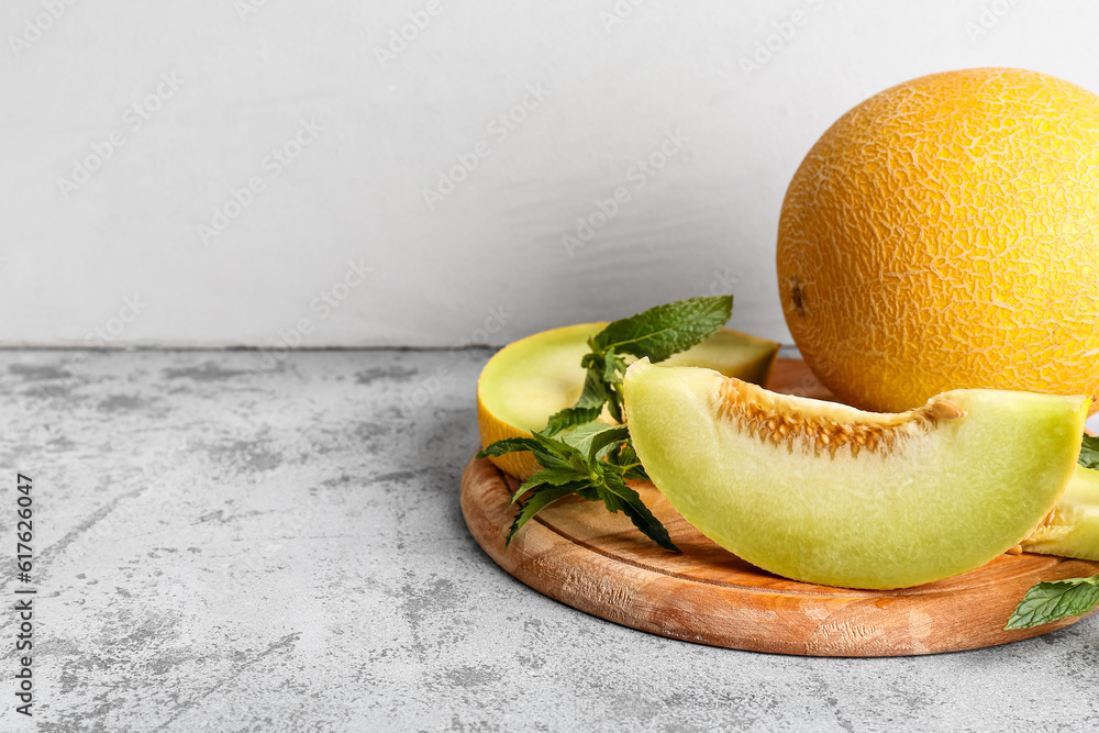 Sweet melon and wooden board with pieces on grey table