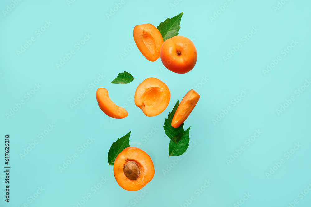 Flying fresh apricot with pieces and leaves on blue background