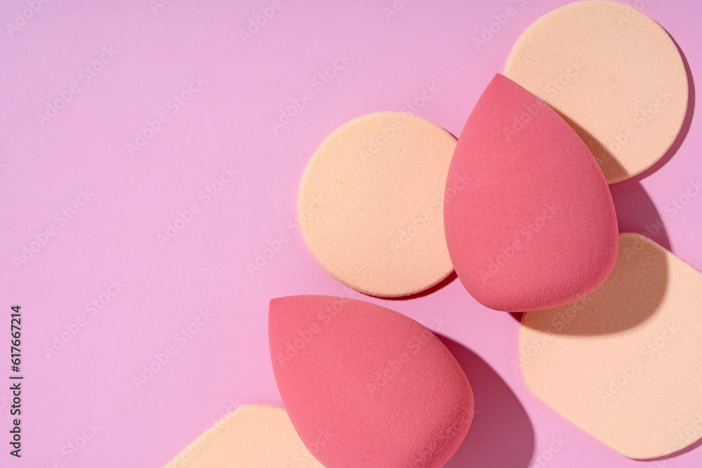 Multiple egg-shaped makeup sponges placed on a pink background.