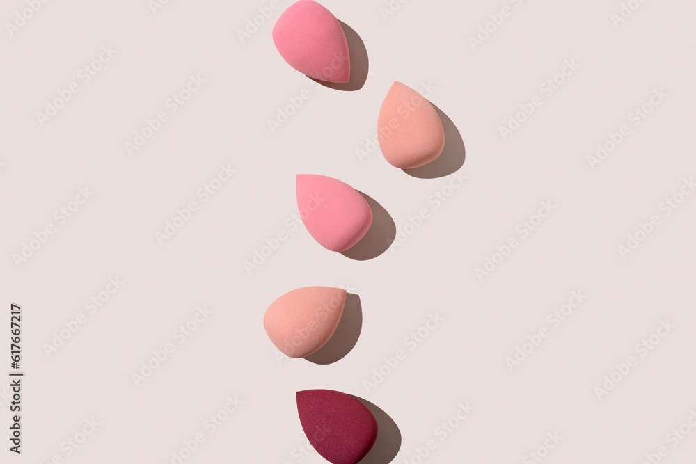 Multiple egg-shaped makeup sponges placed on a beige background.