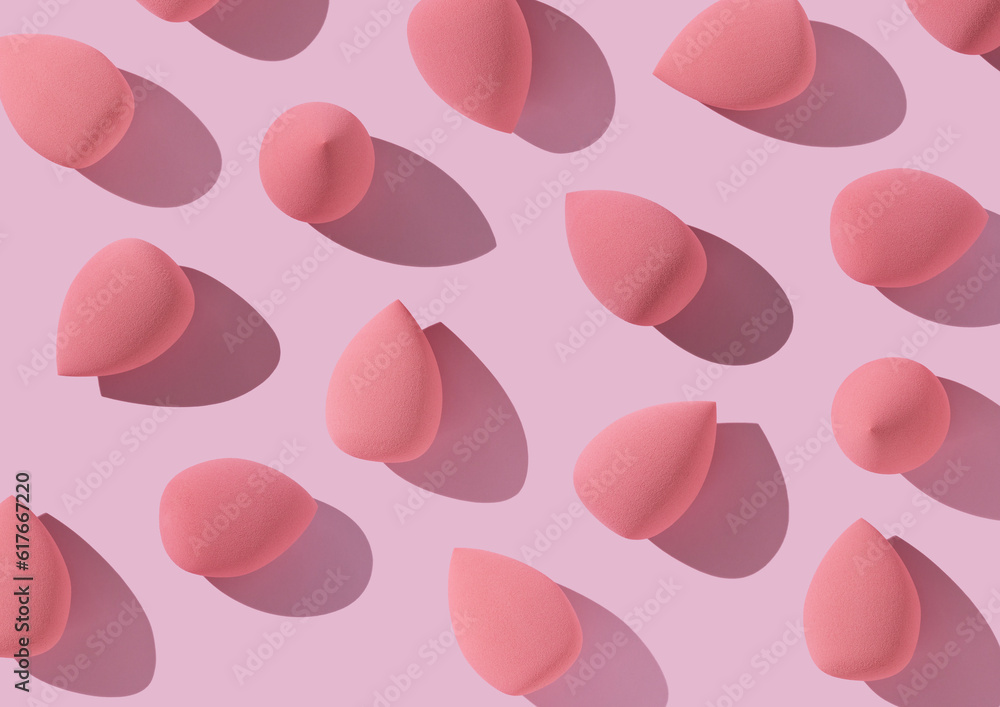 Multiple egg-shaped makeup sponges placed on a pink background.