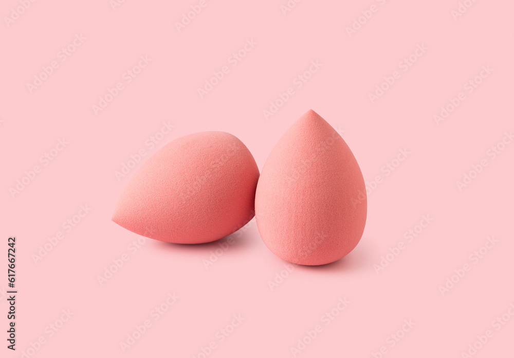 An egg-shaped makeup sponge placed on a pink background.