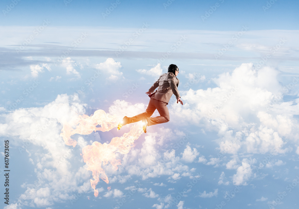 Businessman in suit and aviator hat flying in sky