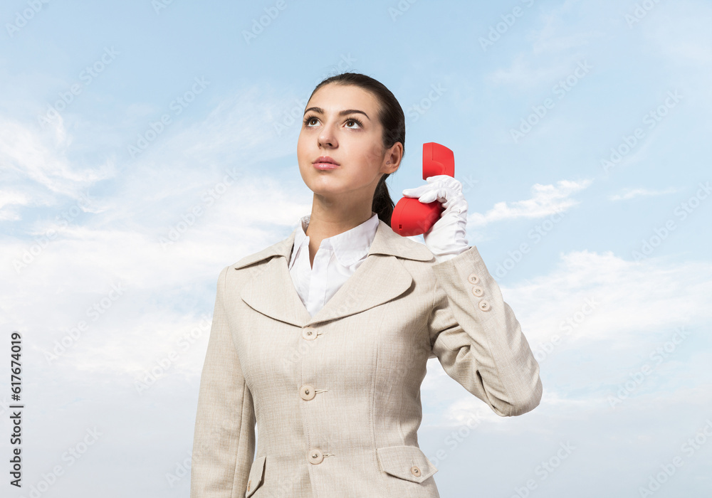 Young business woman holding red retro phone