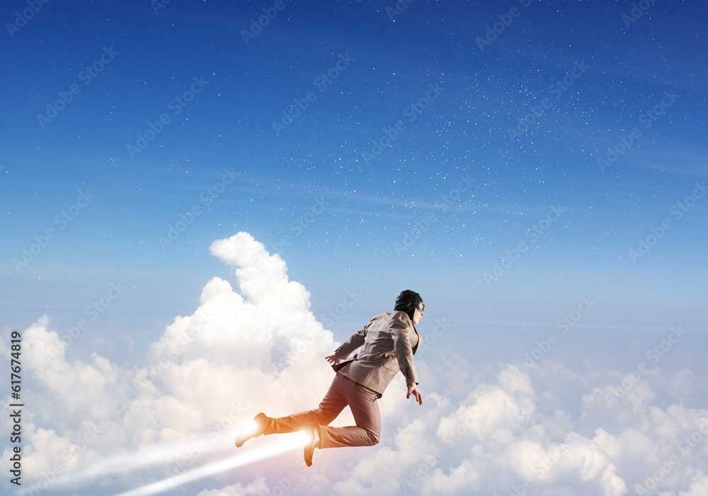 Businessman in suit and aviator hat flying in sky