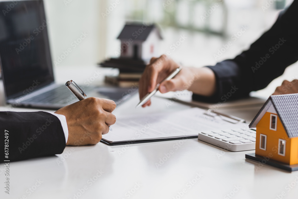 Real estate agent holding pen pointing at contract document for client to sign home purchase agreeme