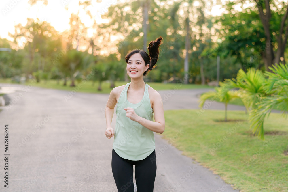 Fit Asian young woman jogging in park smiling happy running and enjoying a healthy outdoor lifestyle