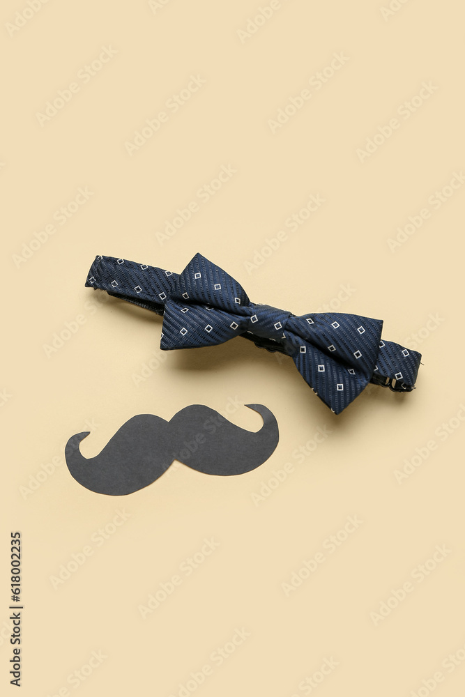 Male bow tie and paper mustache on color background