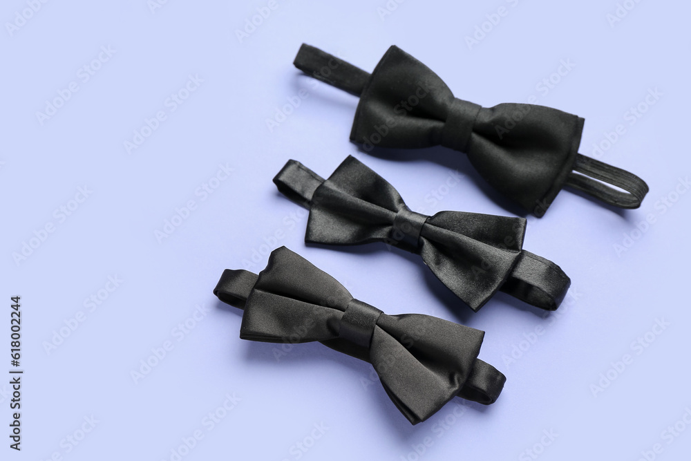 Set of black bow ties on color background