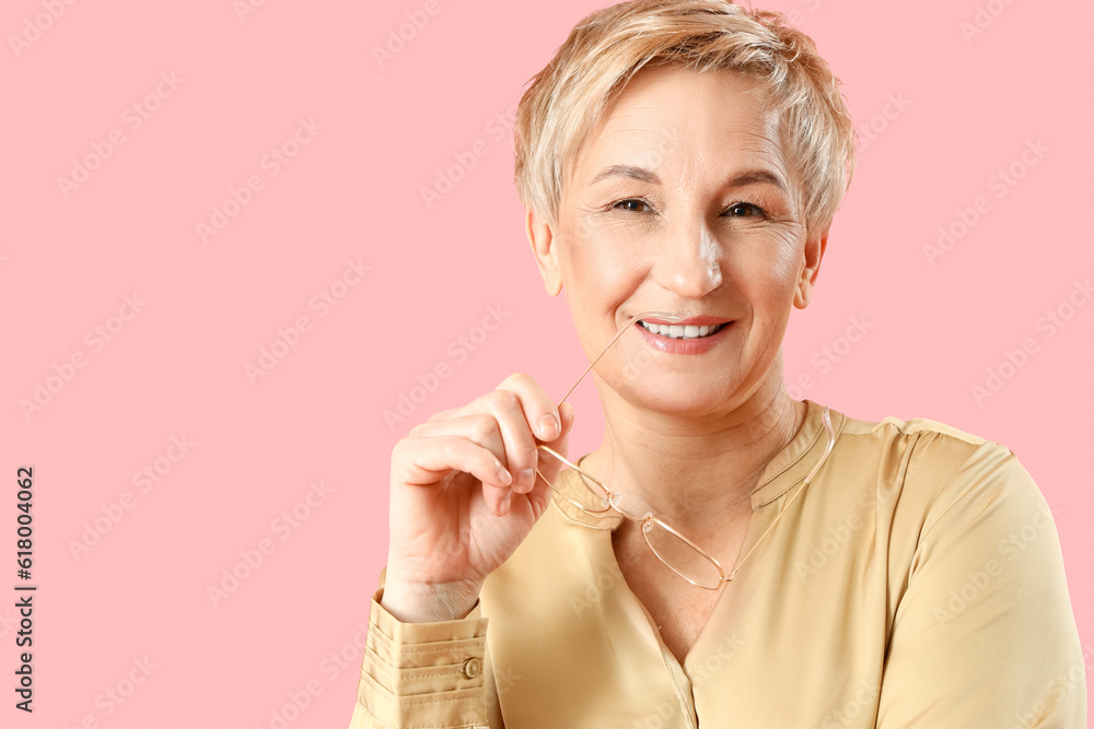 Dreaming mature woman with eyeglasses on pink background