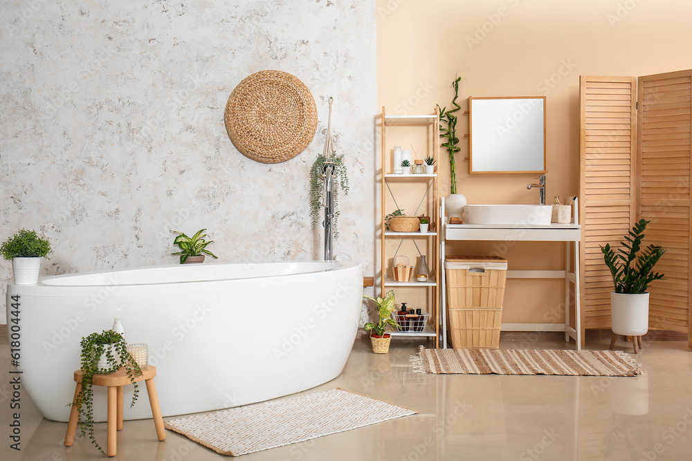 Interior of bathroom with sink, bathtub and houseplants