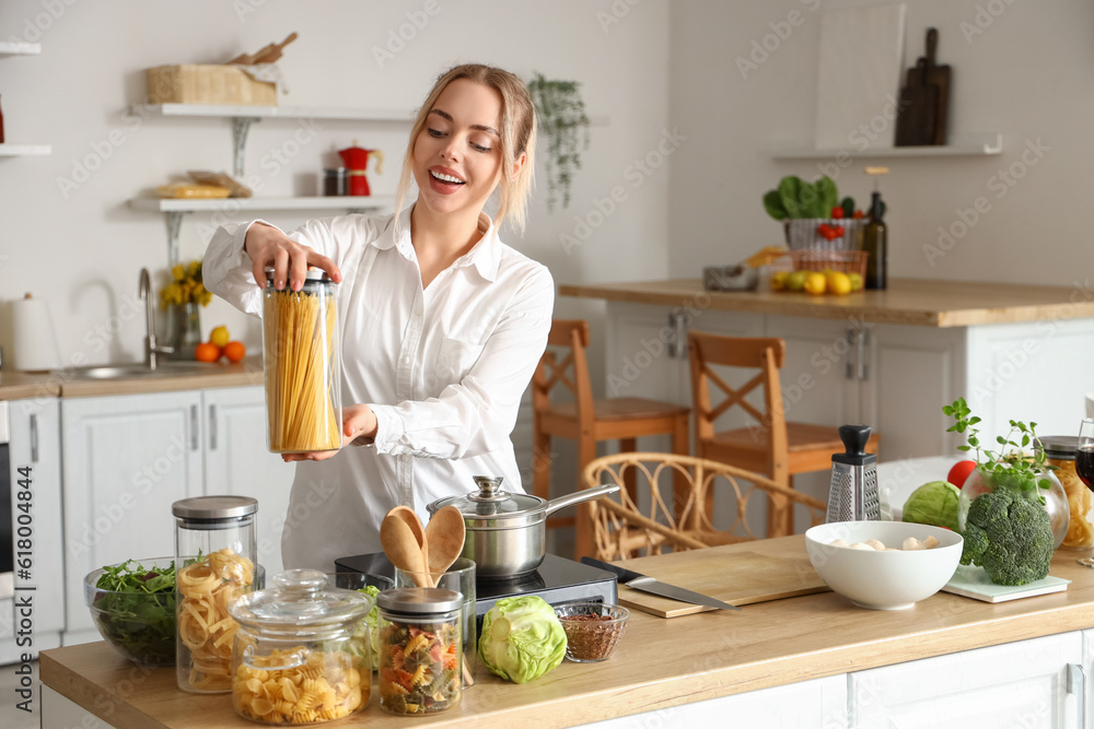 Young woman with raw pasta in kitchen