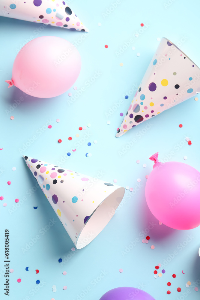 Party hats and balloons on pale blue background