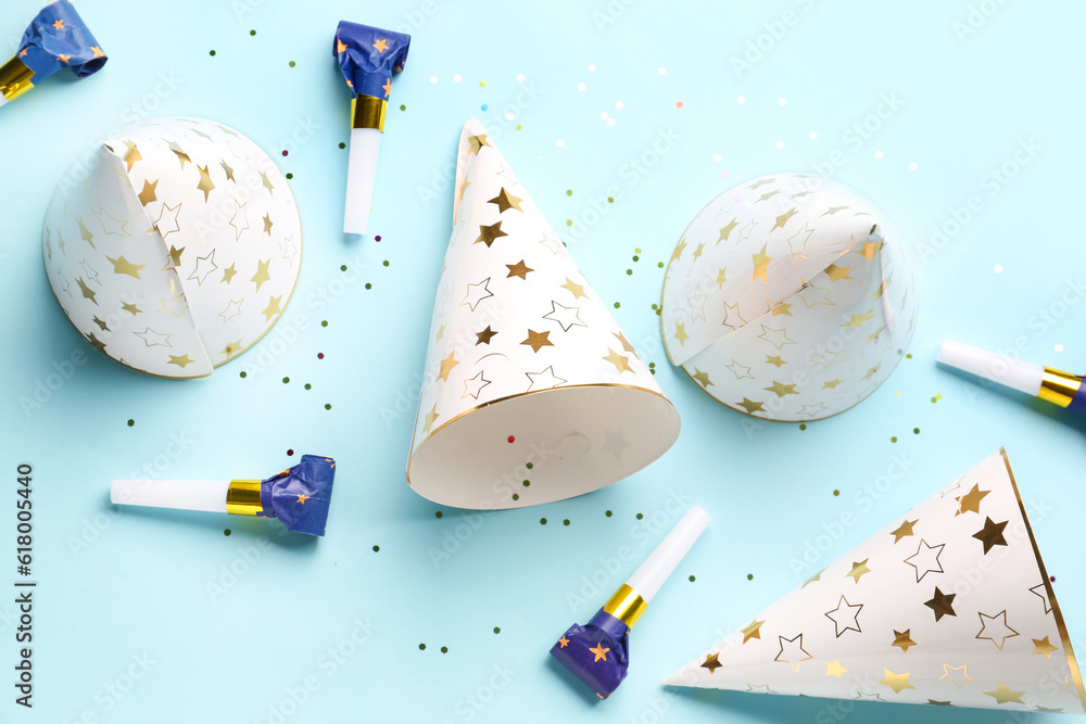 Composition with party hats and whistles on pale blue background