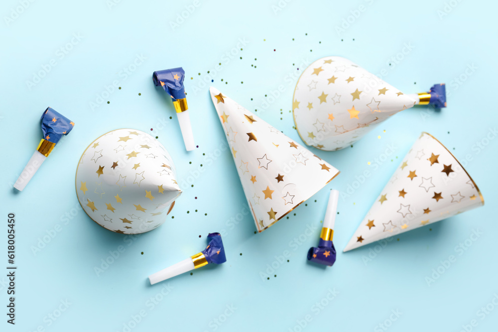 Composition with party hats and whistles on pale blue background