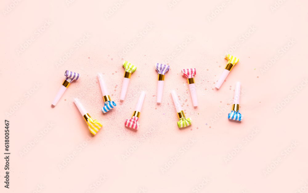 Composition with whistles and sequins for birthday party on pale pink background