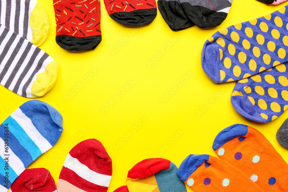 Frame made of different cotton socks on yellow background, closeup