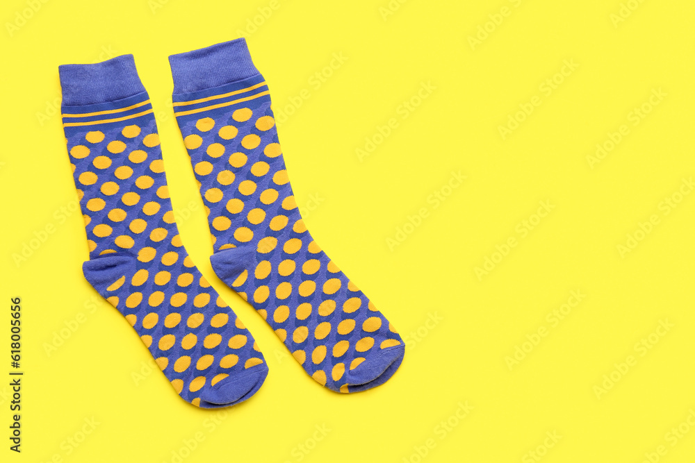 Pair of stylish socks on yellow background