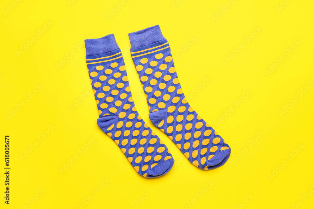 Pair of stylish socks on yellow background