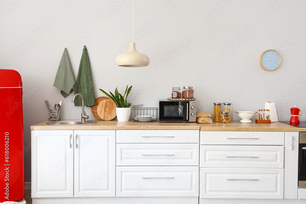 Interior of light kitchen with red fridge and counters