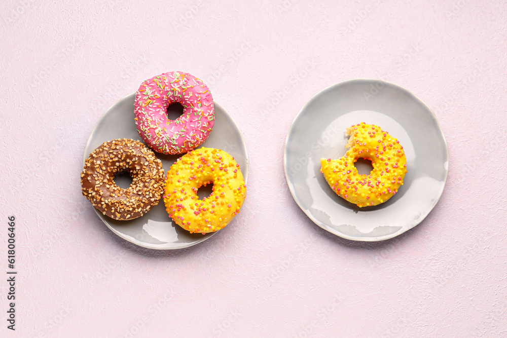 Plates with sweet donuts on light background