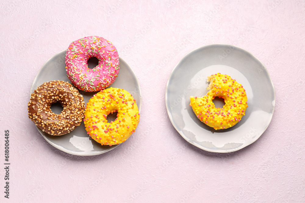 Plates with sweet donuts on light background