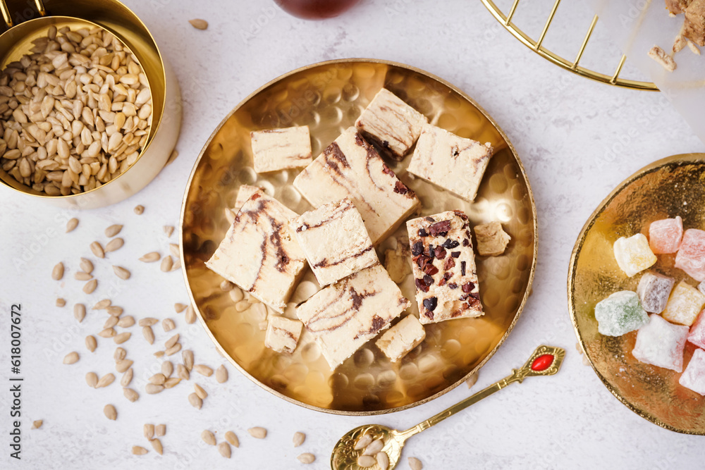 Plate with pieces of tasty marble halva on light background