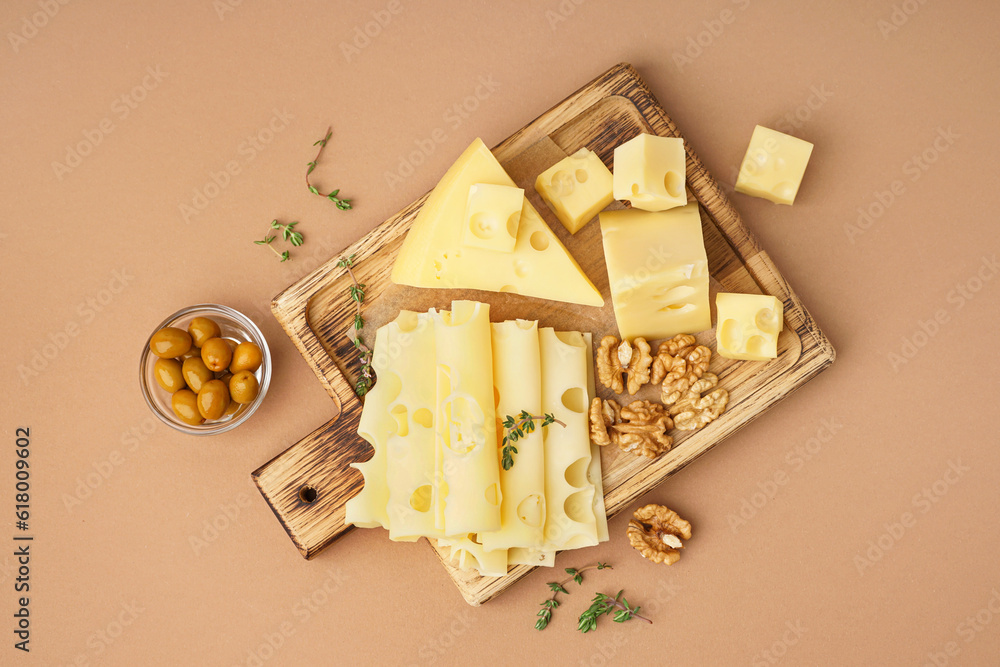 Board with pieces of Swiss cheese and walnut on brown background