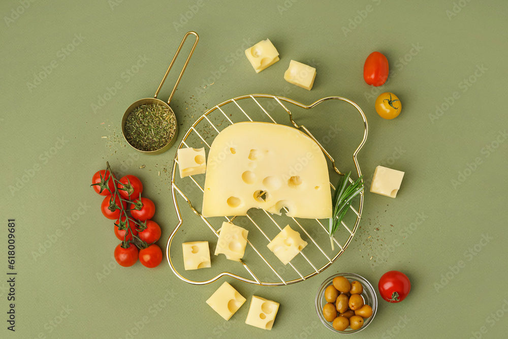 Stand with pieces of Swiss cheese and olives on green background