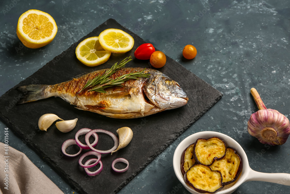 Slate board with tasty grilled dorado fish on grey background