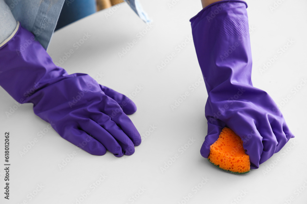 Woman in purple rubber gloves cleaning table with sponge