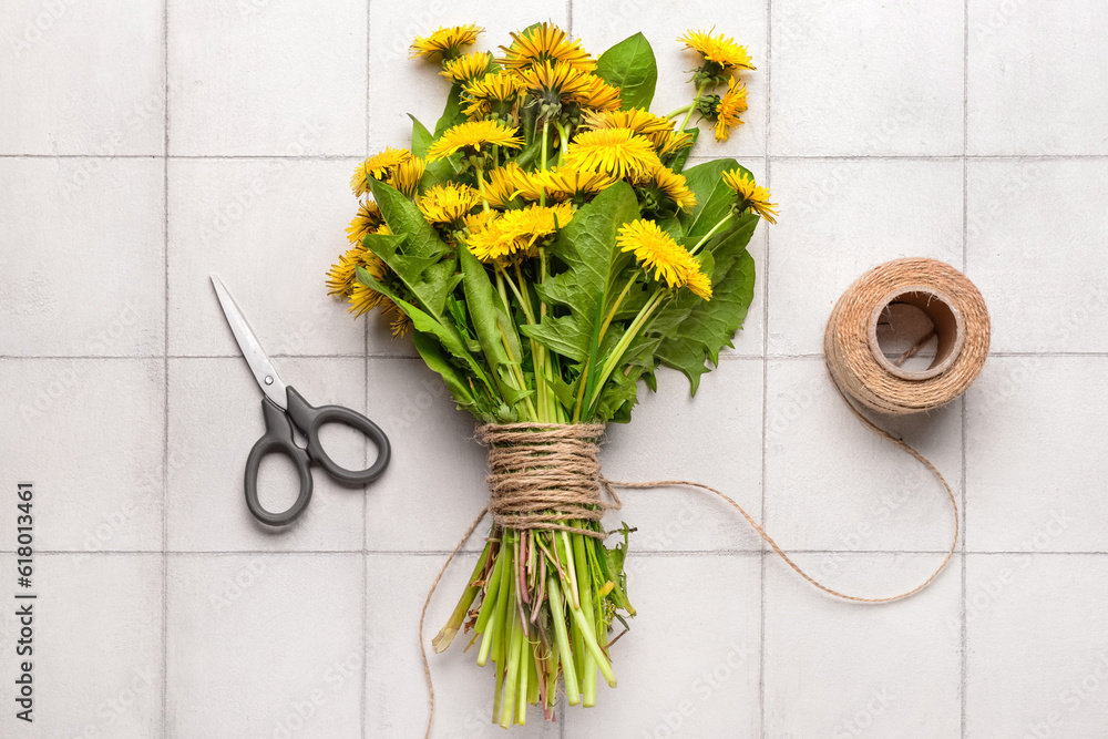 Bouquet of beautiful dandelion flowers, rope and scissors on light tile background