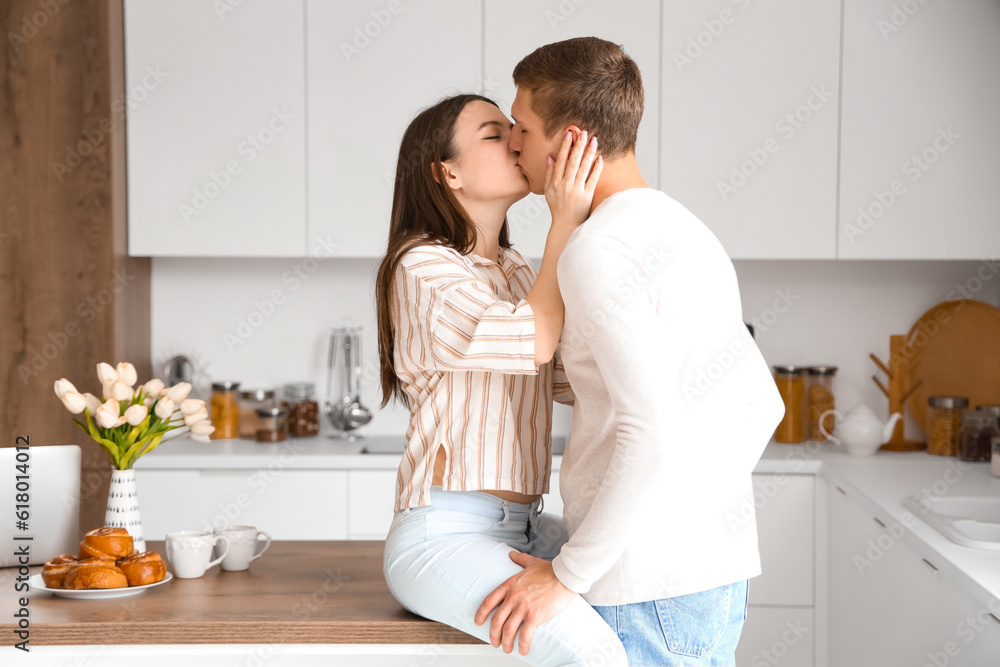 Happy young couple kissing in kitchen