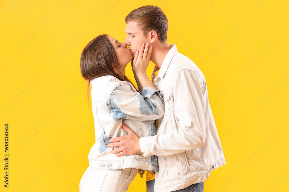 Happy young couple kissing on yellow background