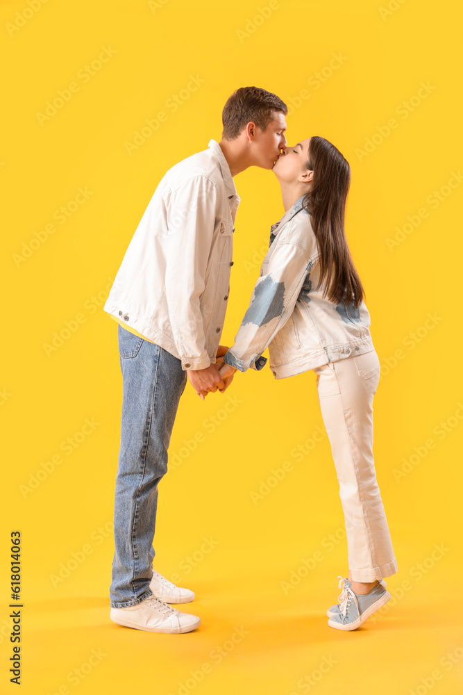 Happy young couple kissing on yellow background