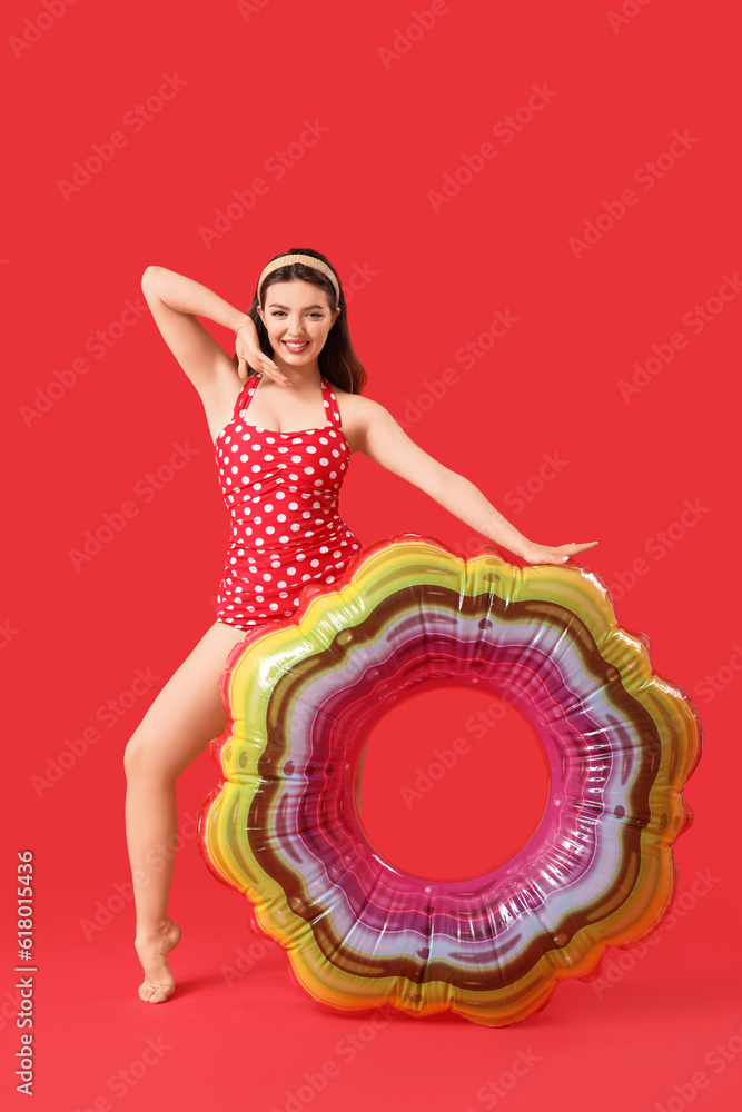 Young woman with swim ring on red background