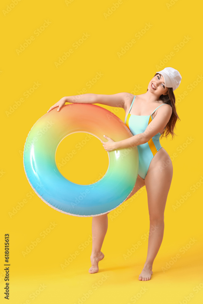 Young woman with swim ring on yellow background