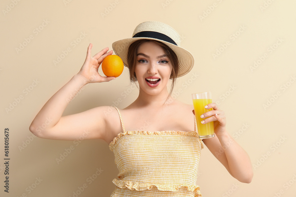 Young woman with glass of juice and orange on beige background