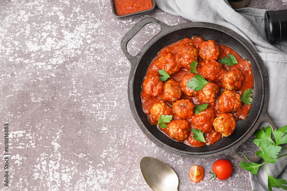 Frying pan of tasty meat balls with tomato sauce and parsley on grey background