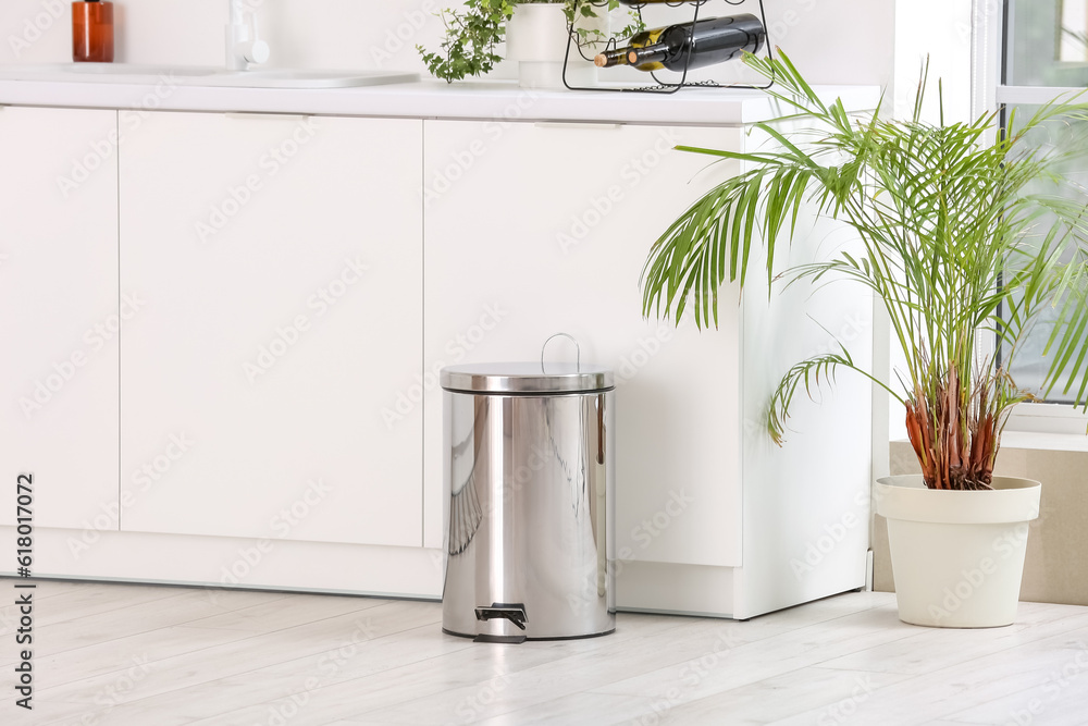 Metallic trash bin in interior of light kitchen