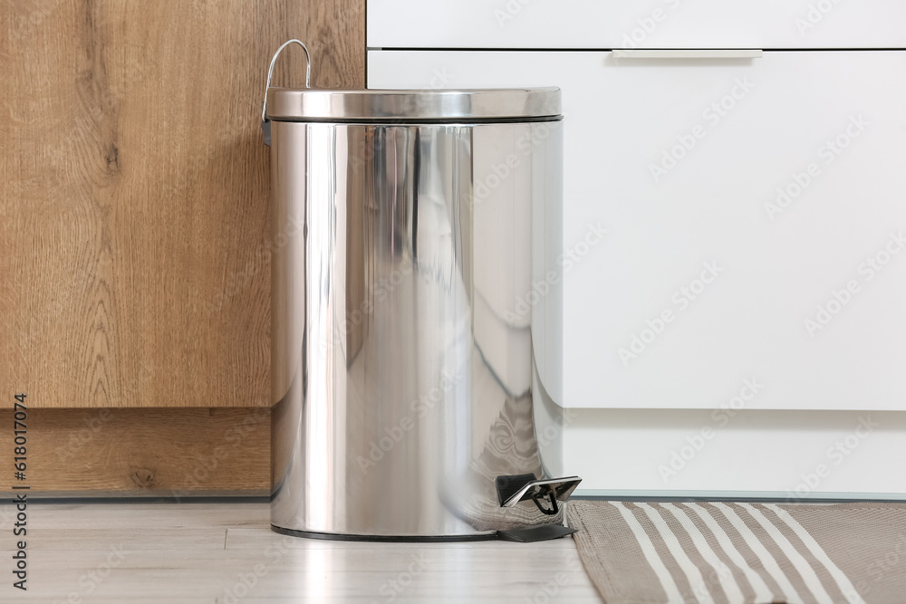 Metallic trash bin in interior of light kitchen