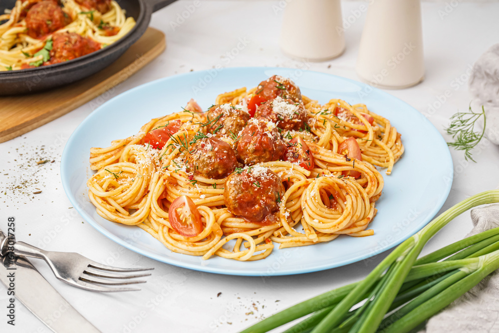 Plate of boiled pasta with tomato sauce and meat balls on white table