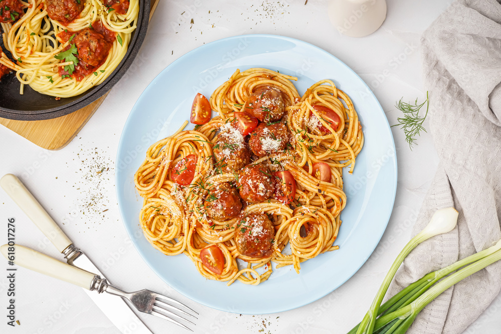 Plate of boiled pasta with tomato sauce and meat balls on white table