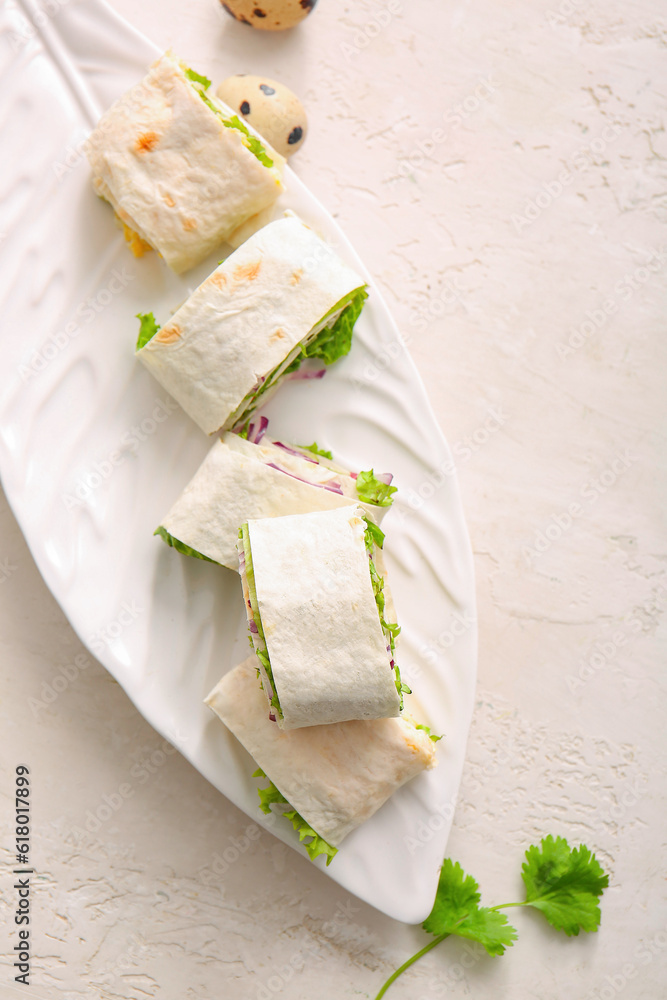 Plate of tasty lavash rolls on light background