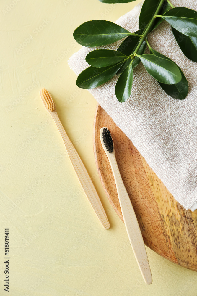 Bamboo tooth brushes and towel on beige background, top view